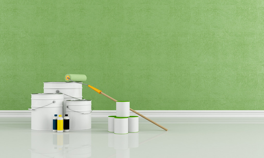 Paint tins and a roller ready against a freshly painted green wall